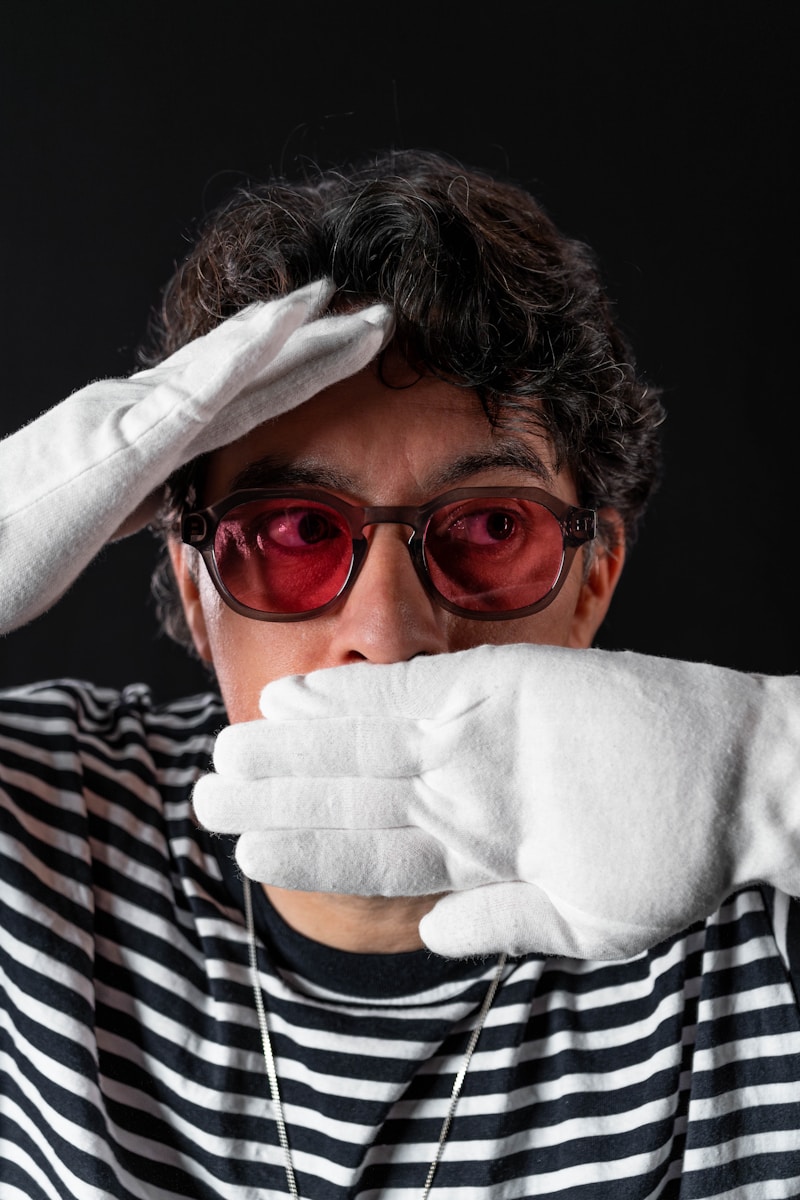 Photo by Malcolm Broström a woman in a striped shirt and white gloves covering her eyes
